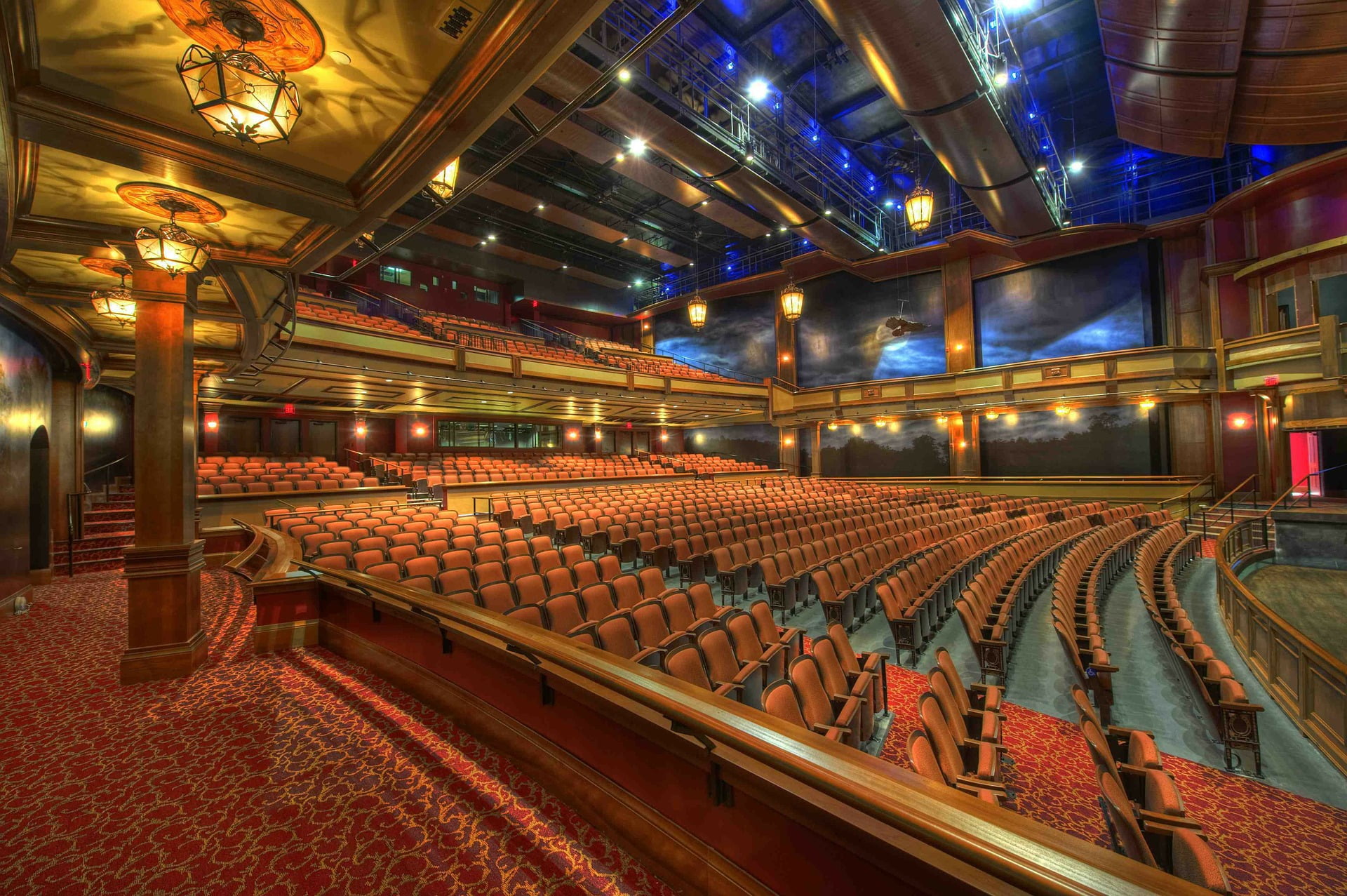 A grand theatre hall with tiered seating, a high ceiling, and gallery seating