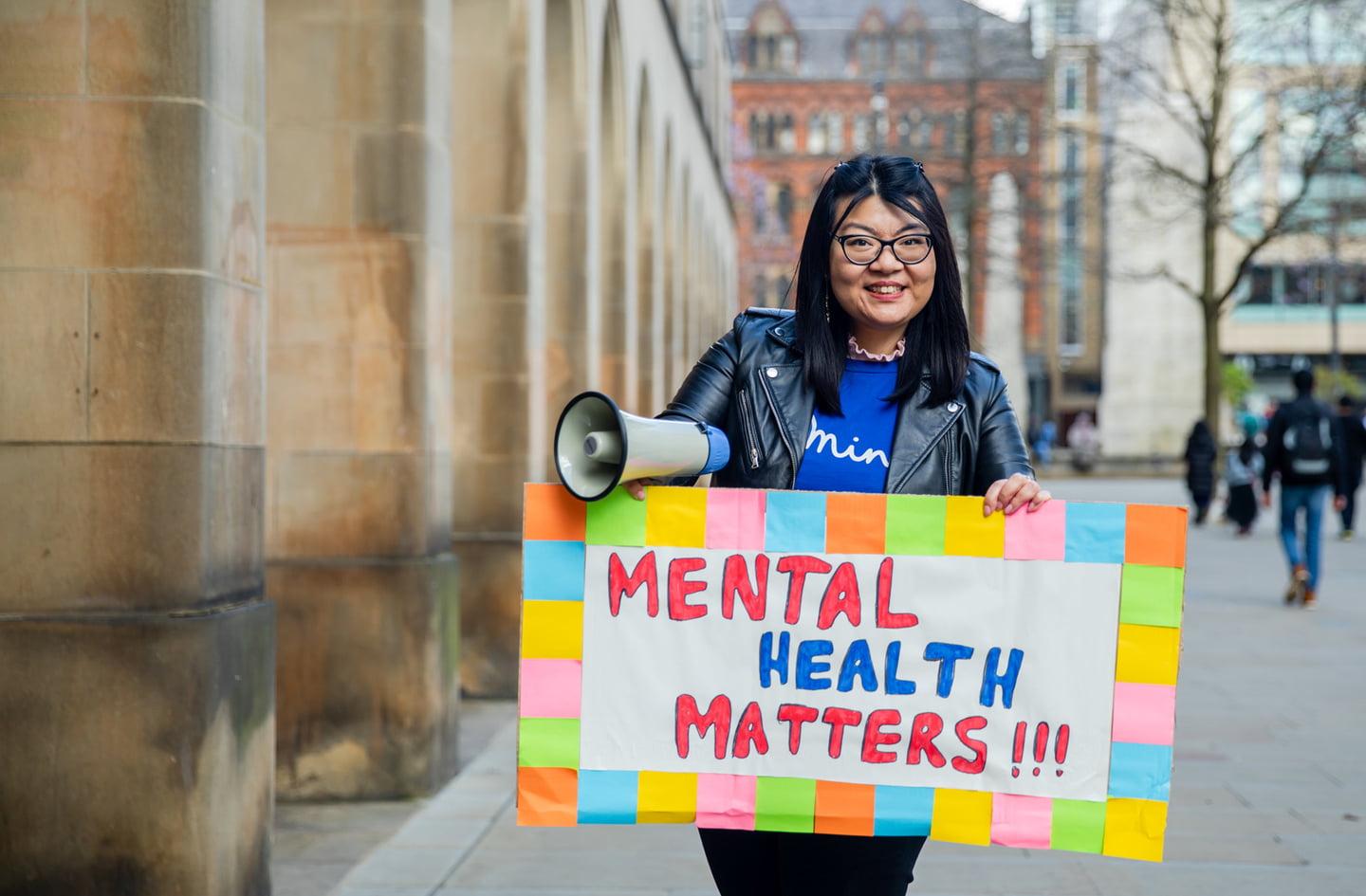 An asian woman holding a megaphone and placard with reads 'mental health matters'