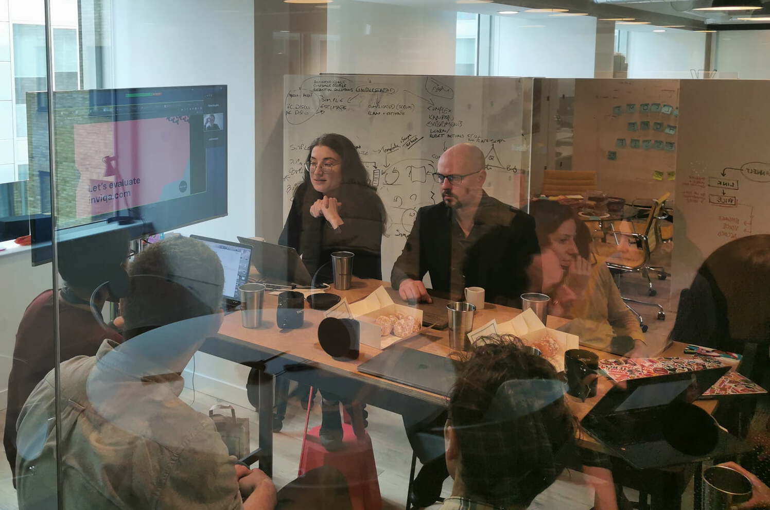 A through-the-window image of a meeting taking place in a glass room